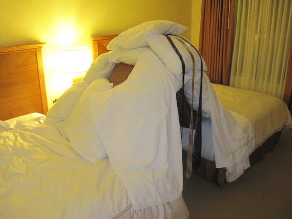 A pillow fort created in the gap between two hotel room beds.