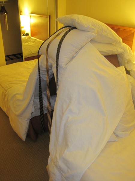 A pillow fort created in the gap between two hotel room beds.