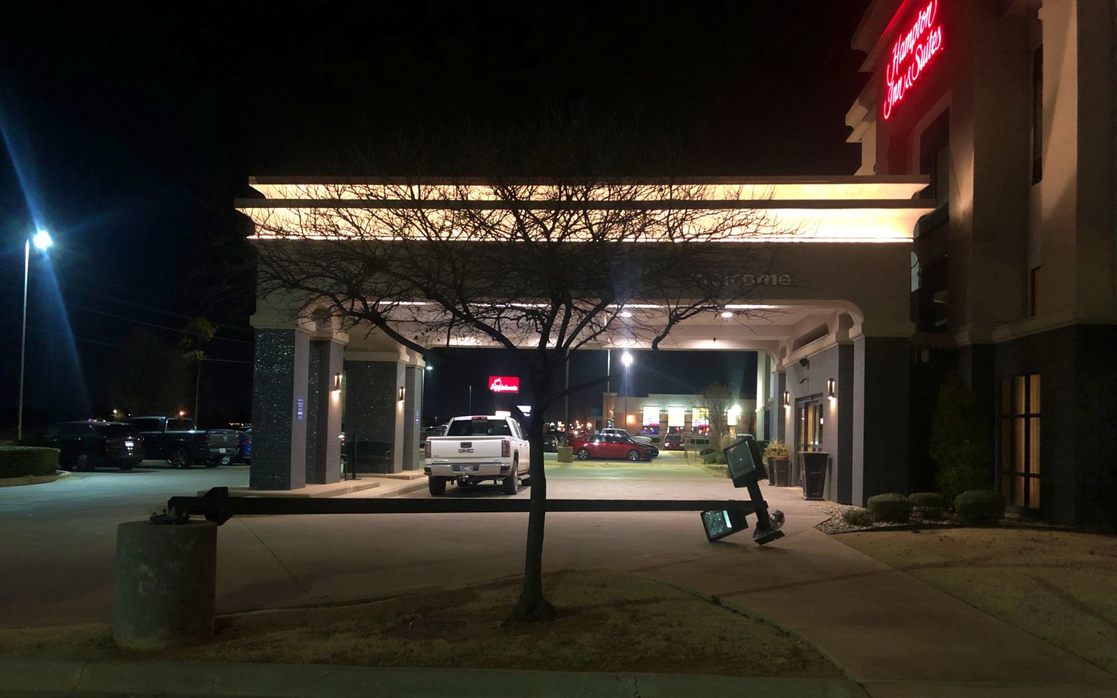 The Hampton Inn Altus at night, with a knocked-over lamp pole in the parking lot, and Applebee's in the background