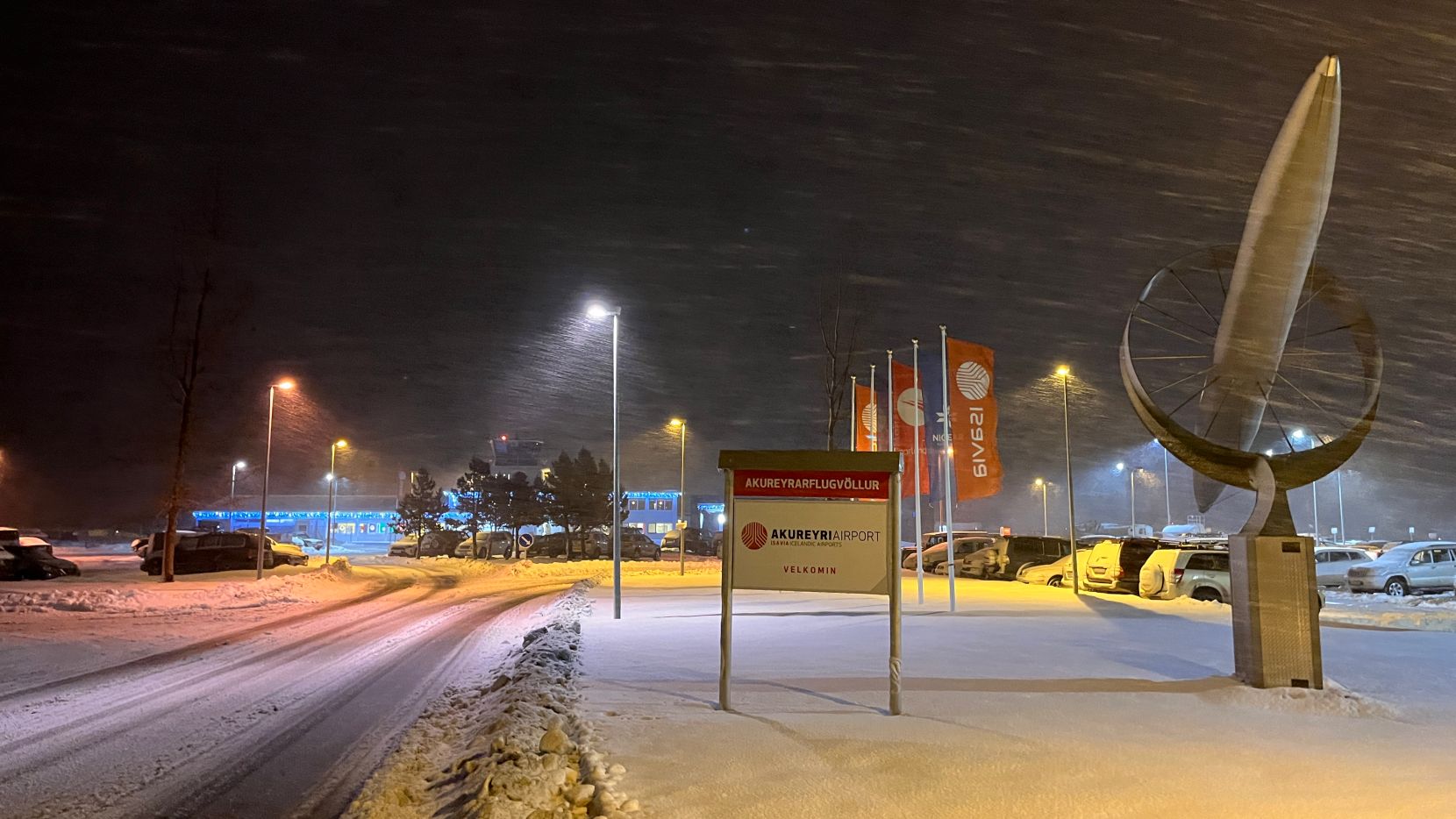 Front entrance of AEY, showing an Akureyri Airport sign and a sculpture, with the terminal in the background.