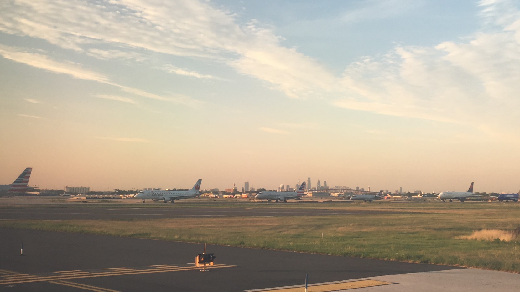 Planes lined up at PHL with the Philadelphia skyline in background.