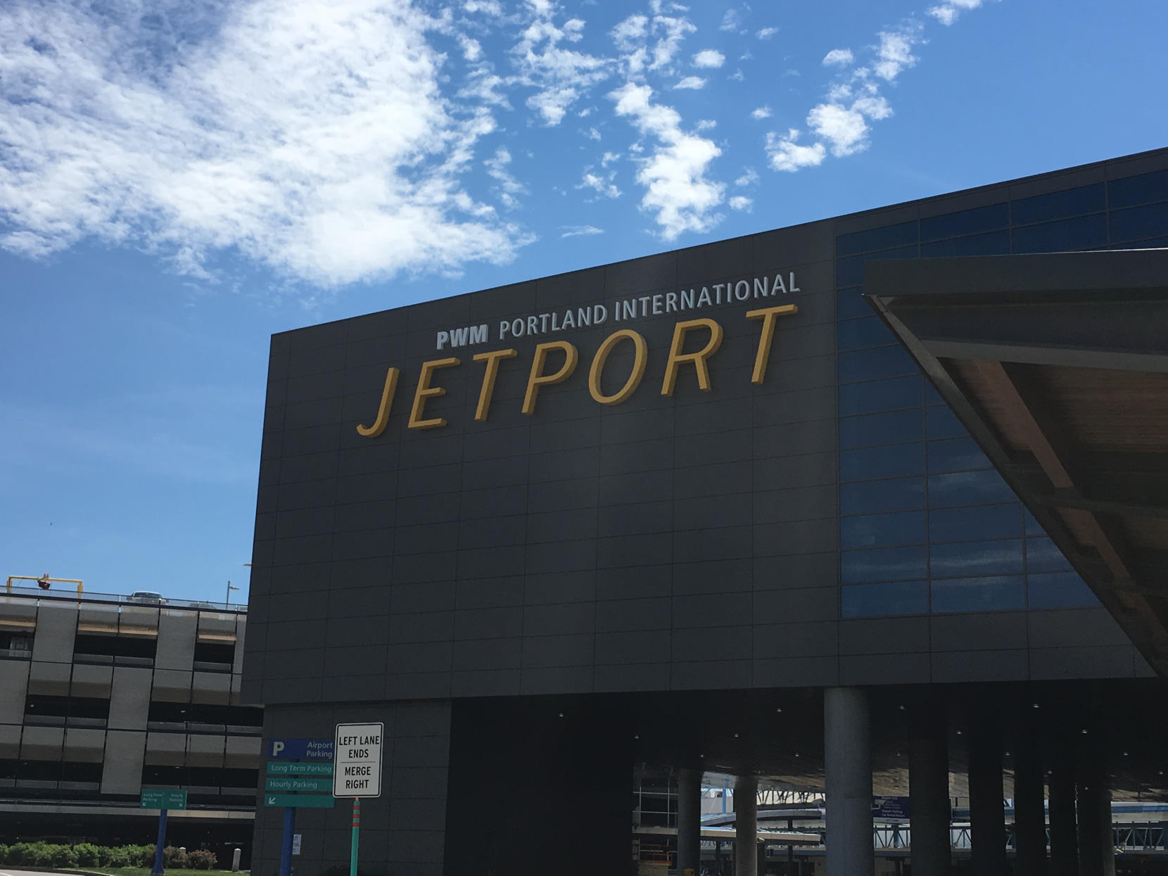 Terminal overhanging the arrivals/departure loop at PWM, with a large sign on the building reading 'PWM Portland International Jetport'.