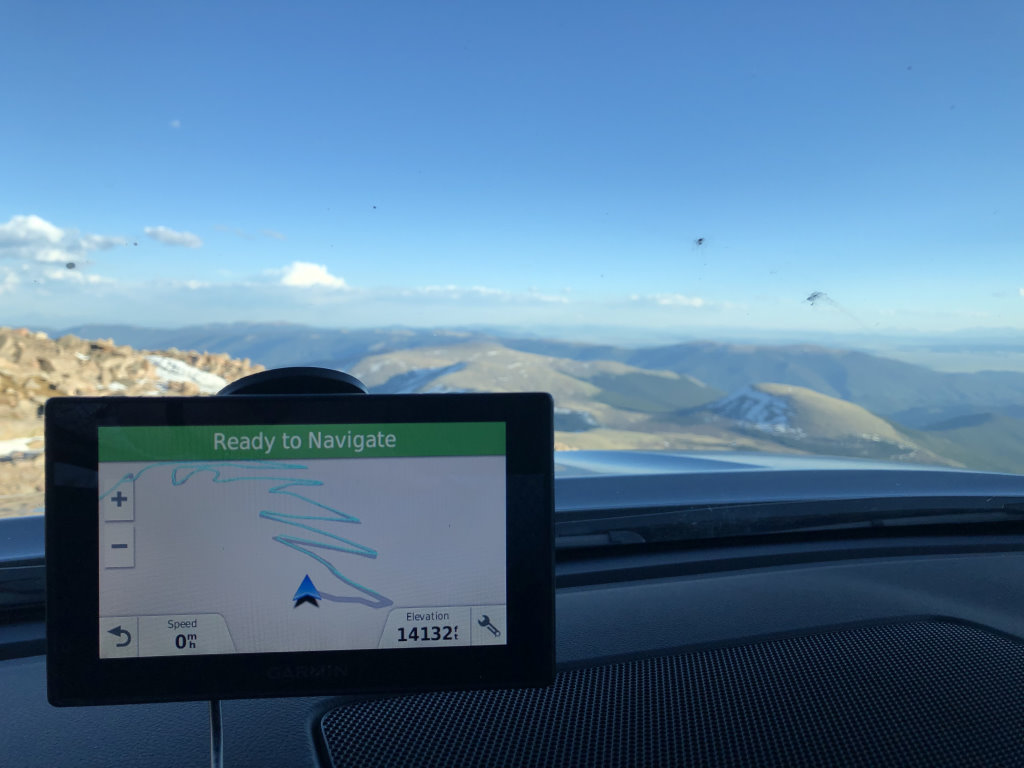 A windshield-mounted GPS on top of Mount Evans, Colorado, showing an elevation of 14132 feet.