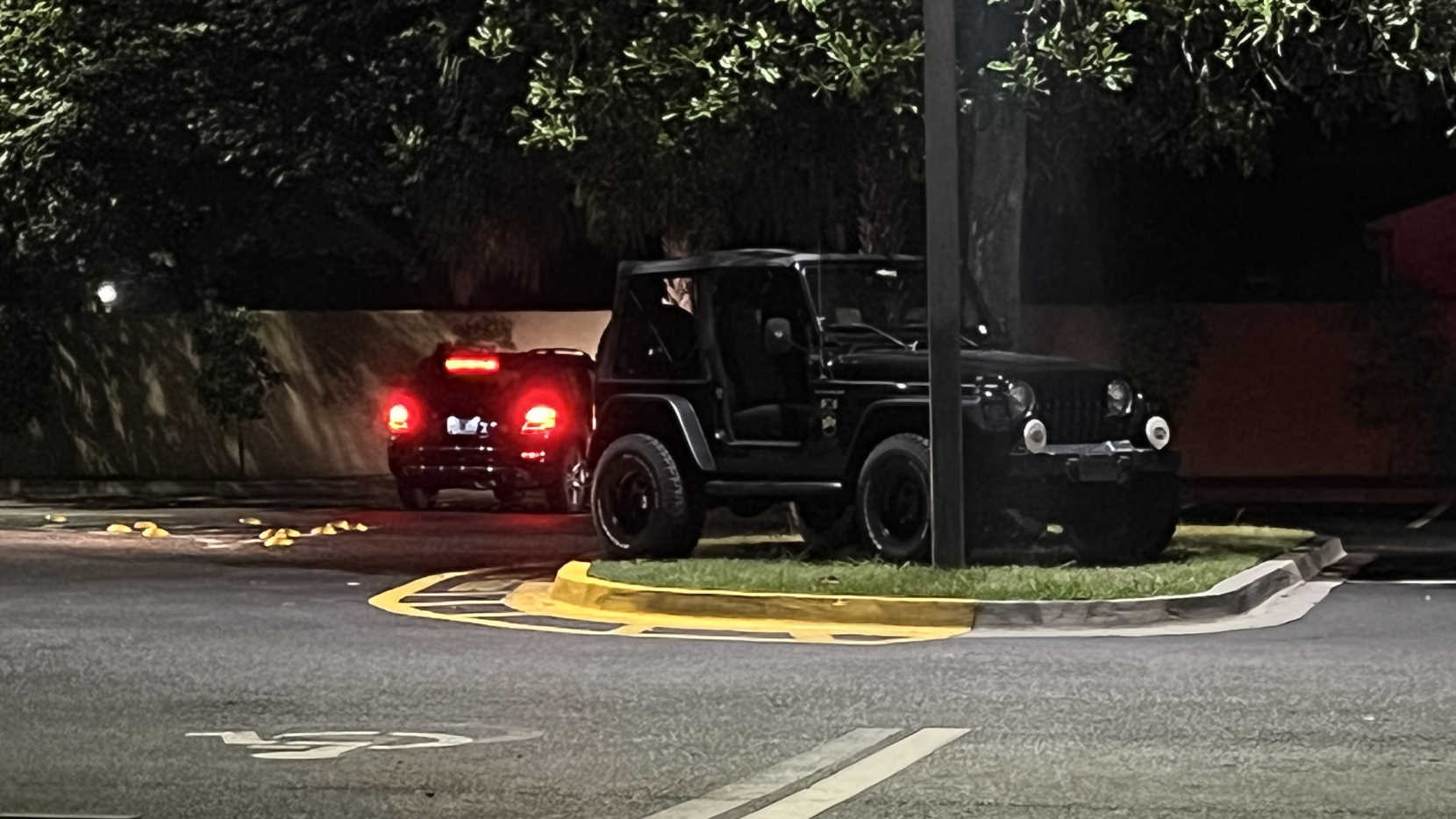 A Jeep, parked on a parking lot grass island.