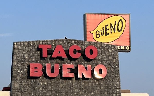 A bird next to a Taco Bueno speech bubble sign