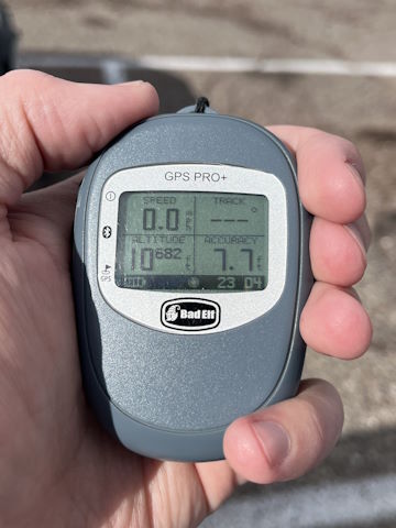 A handheld GPS showing an altitude of 10682 feet, with 7.7 foot accuracy.